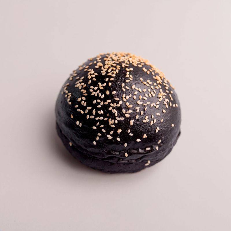 A black burger bun topped with sesame